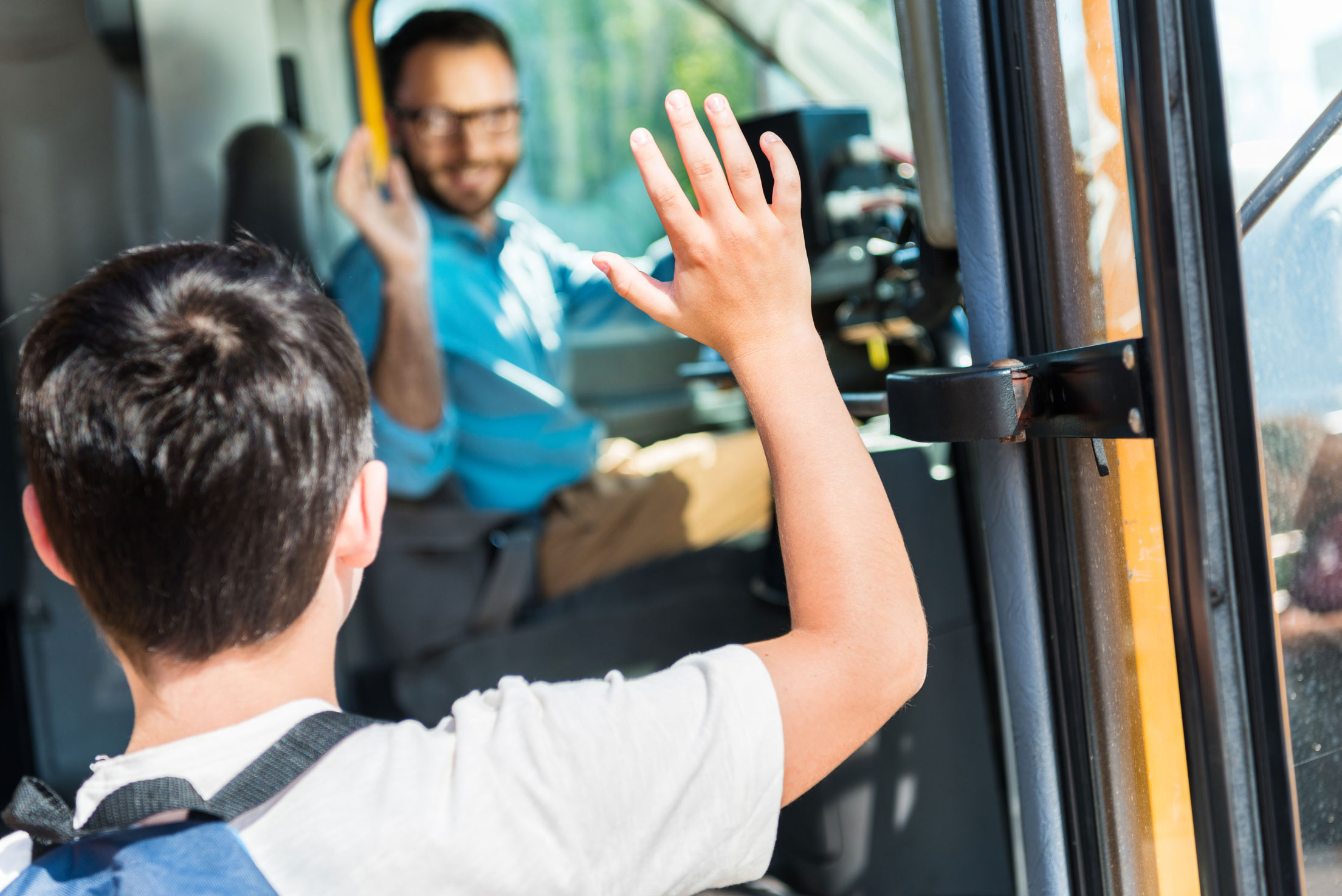 Kind winkt Busfahrer zu