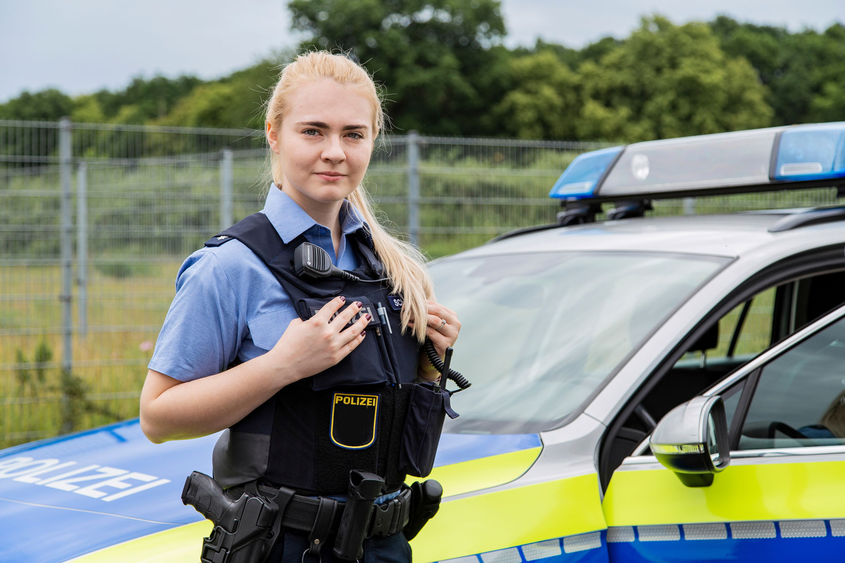 Polizistin vor dem Polizeiauto